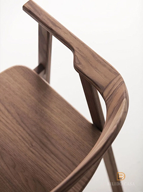 Close-up of a custom wooden chair’s armrest and seat frame, highlighting fine wood grain and artisanal design.